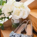 A pair of wedding shoes and a vase of flowers on a staircase.