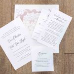 A set of wedding invitations with intricate details on a wooden floor.