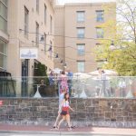 A woman is skateboarding in front of a building during a birthday party.