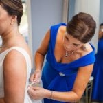 A candid bride getting ready for her wedding in front of a mirror.