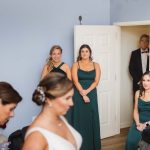 On the day of the wedding, the bride and her bridesmaids pose candidly in the doorway while preparing for the ceremony.