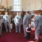 Groom and groomsmen prepare for wedding with a little boy.