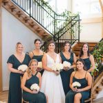 A wedding party poses in front of a staircase.