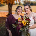 Two brides posing for a wedding portrait in the fall.