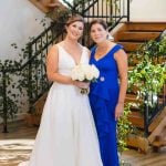 Two brides posing for a wedding portrait in front of a staircase.