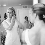 A candid bride preparing for her wedding in front of a mirror.