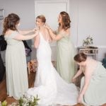 A candid wedding preparation scene of a bride and her bridesmaids in a room.