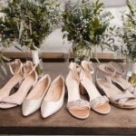 Details of bridesmaids' shoes and bouquets on a wedding table.