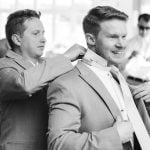 A man is candidly adjusting his tie in preparation for a wedding.