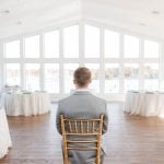 A candid man sitting in a chair at a wedding reception.