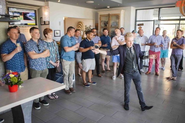 A man in a suit standing in front of a group of people at a birthday party.