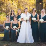 Bridesmaids in emerald dresses posing for a wedding portrait.