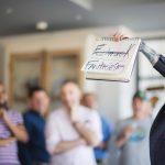 A group of people holding up a sign that reads 'employee engagement' at a celebration.