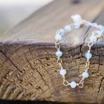 A wedding bracelet with blue and white beads on top of a piece of wood.