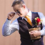 A man in a vest holding flowers at a wedding ceremony.