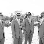 A group of groomsmen posing for a wedding portrait on a dock.