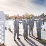 A wedding portrait of groomsmen standing on a dock.