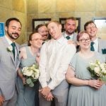 A candid group of groomsmen preparing for a wedding pose in a bathroom.