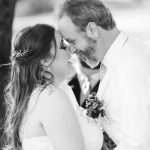 A black and white photo capturing the intimate wedding ceremony as the bride and groom share a kiss.