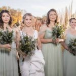 Four bridesmaids with bouquets in front of a lake at a wedding.