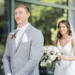 A candid wedding couple standing in front of a glass door.