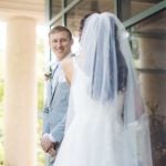 A candid wedding moment, with the bride and groom looking at each other in front of a building.