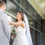 A candid bride and groom smiling at each other during their wedding preparation.