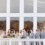 A group of bridesmaids and groomsmen posing for a wedding portrait on the balcony of a building.