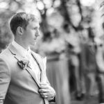 A black and white portrait of a groom at a wedding.