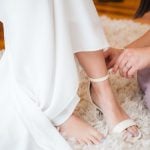 A candid woman preparing for her wedding by putting on her shoes.