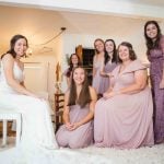 The bride and her bridesmaids candidly pose for a wedding photo.