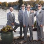 A group of groomsmen posing for a wedding portrait on a dock.