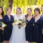 A group of bridesmaids in navy dresses posing for a wedding portrait.