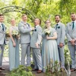 A group of groomsmen posing for a wedding portrait in a garden.