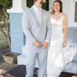 A candid wedding preparation moment captured as the bride and groom stand on the steps of a house.