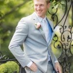 A man in a gray suit is posing for a wedding portrait.