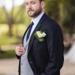 A groom in a tuxedo posing for a wedding portrait.