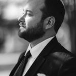 A black and white wedding portrait of a groom in a suit.