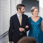 A man and woman in a blue dress walking down a walkway during a wedding ceremony.