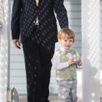 A man in a suit walking with a little boy at a wedding ceremony.