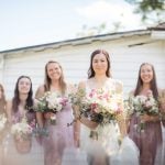 A group of bridesmaids posing for a wedding portrait in front of a house.