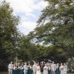 A group of wedding party members posing in front of a tree.