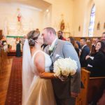 A bride and groom kissing at their wedding ceremony in a church.