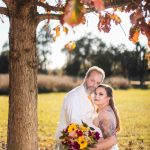 A couple posing under a tree at their wedding.