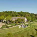 An aerial view of a golf course with a house in the background suitable for a wedding ceremony.