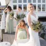 A wedding portrait of a bride and her bridesmaids on a dock.