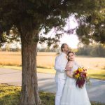 A wedding couple posing under a tree.