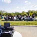 A man is playing a DJ at an outdoor wedding ceremony.