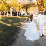 A wedding portrait of a bride and groom walking down a dirt path.