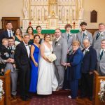 A wedding party posing for a portrait in a church.